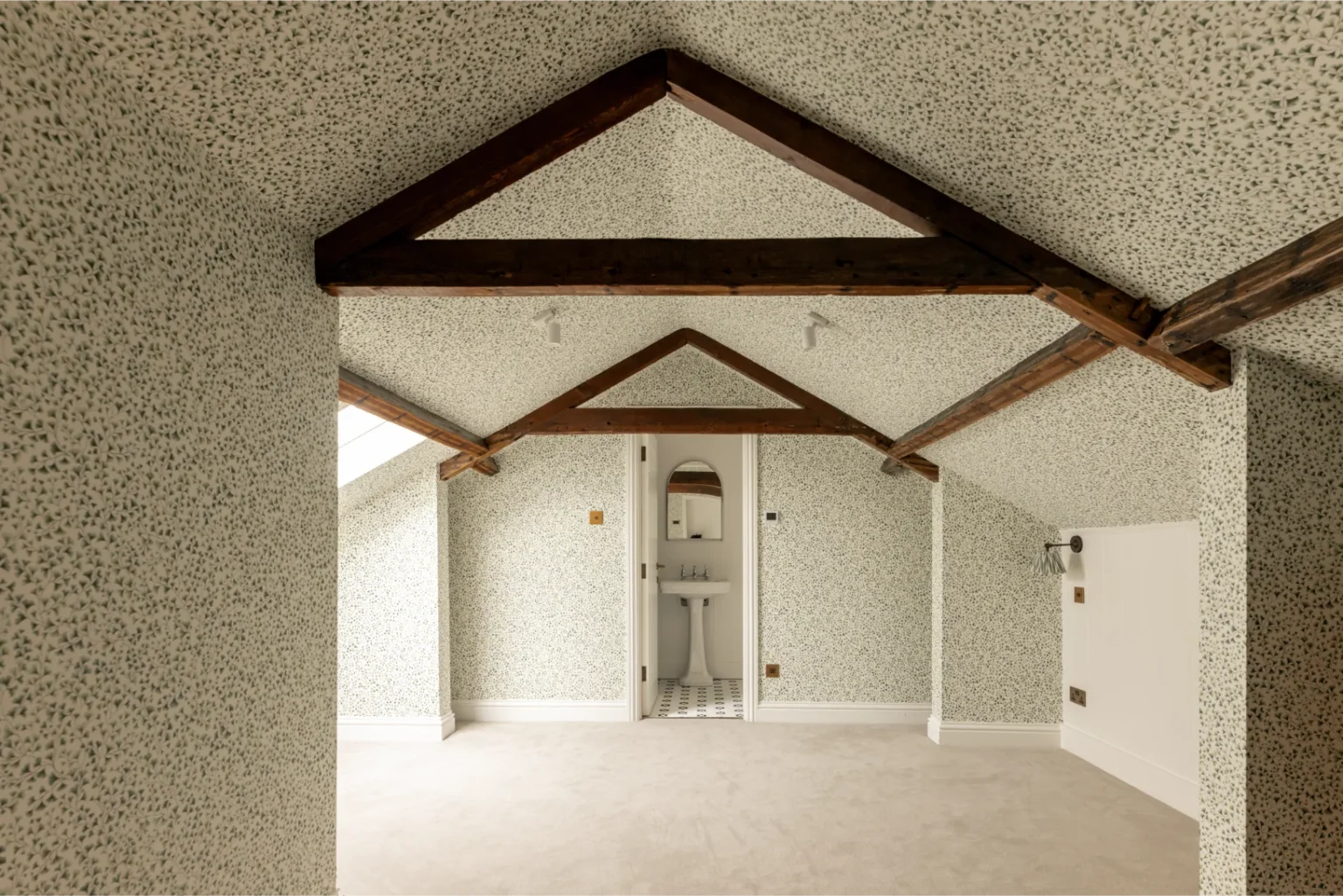 Attic room with wooden beams and patterned walls.