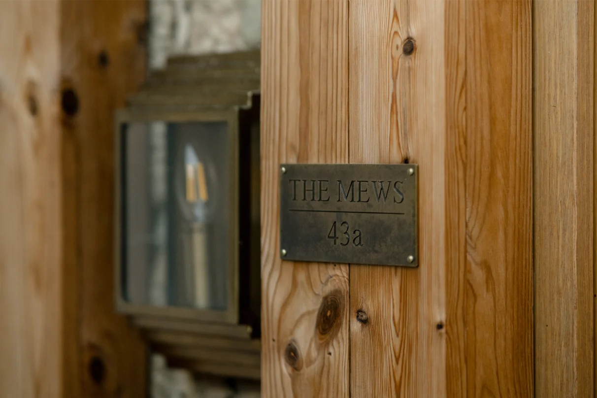 Wooden sign displaying 'The Mews 43a' address.