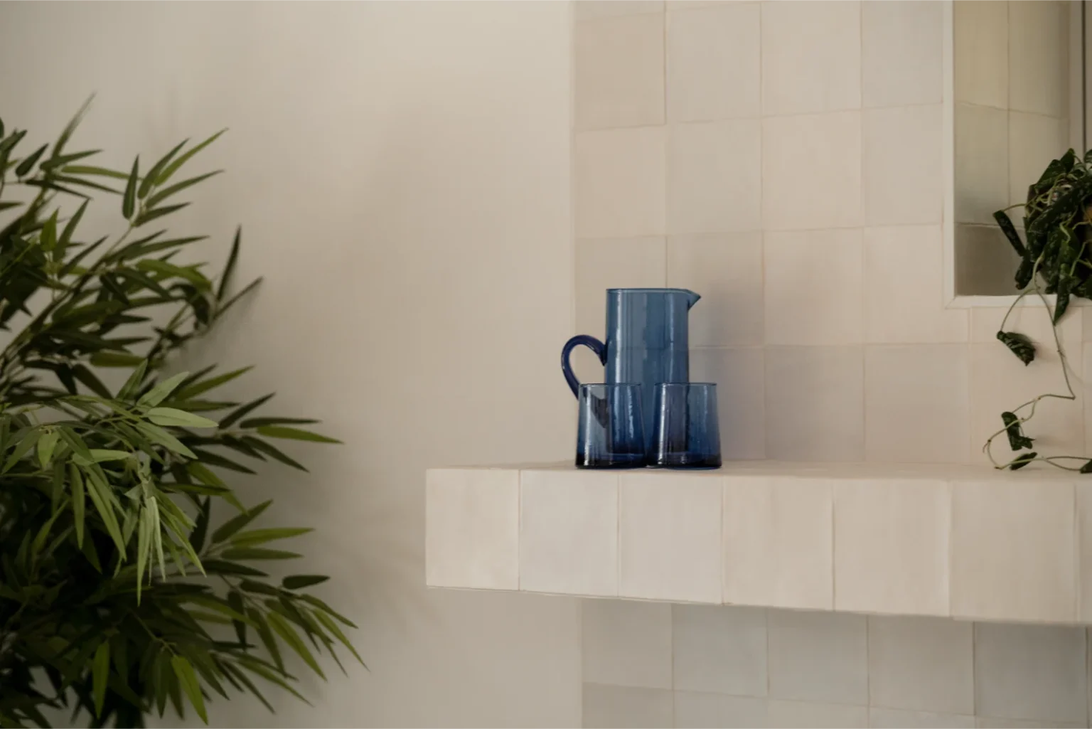 Blue glassware on tiled shelf with plants