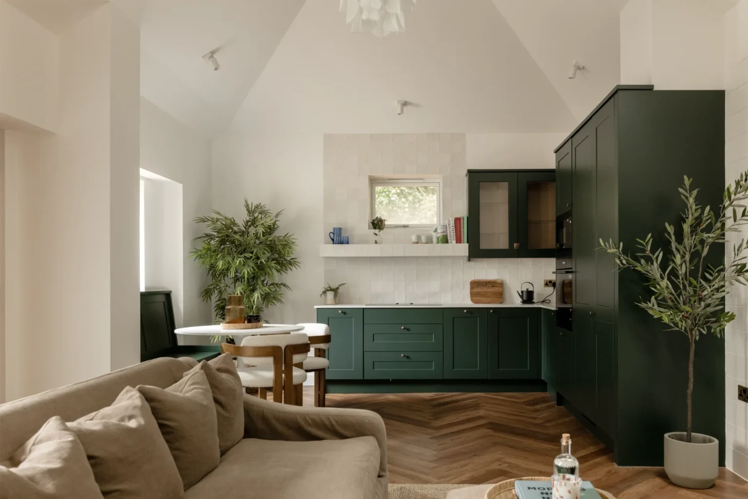 Modern kitchen with green cabinets and plants.