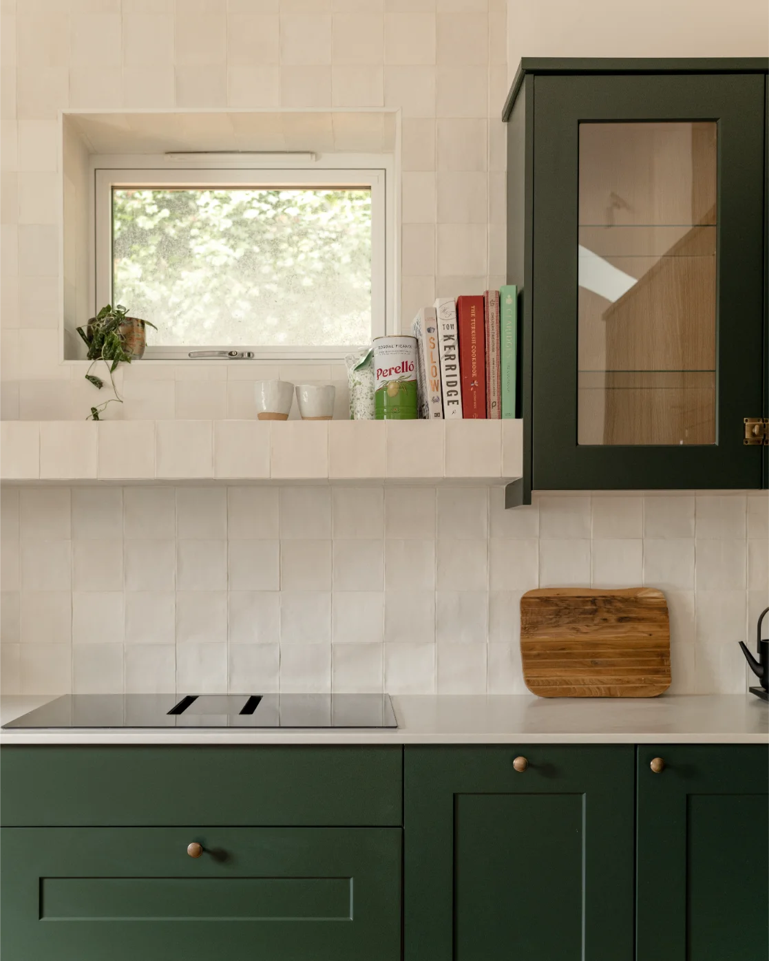 Modern kitchen with green cabinets and white tile.