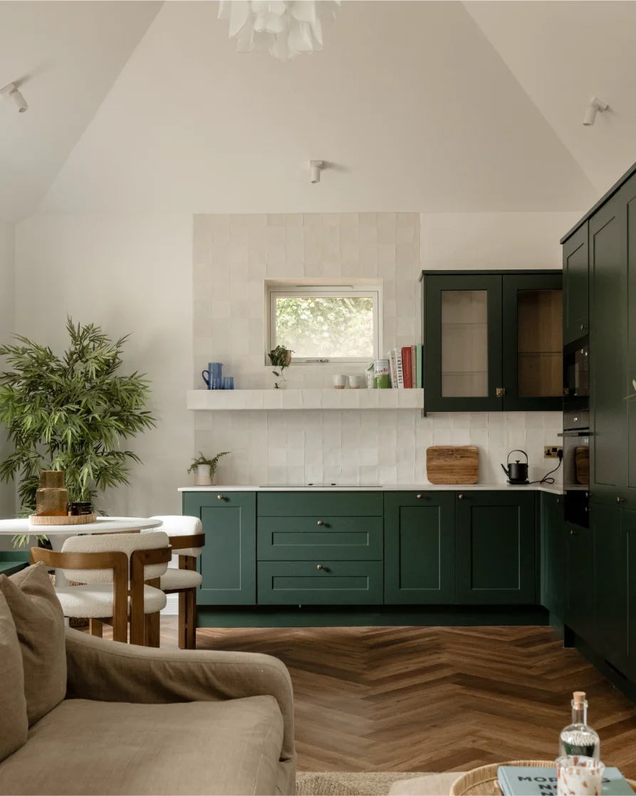 Modern kitchen with green cabinets and wood flooring.