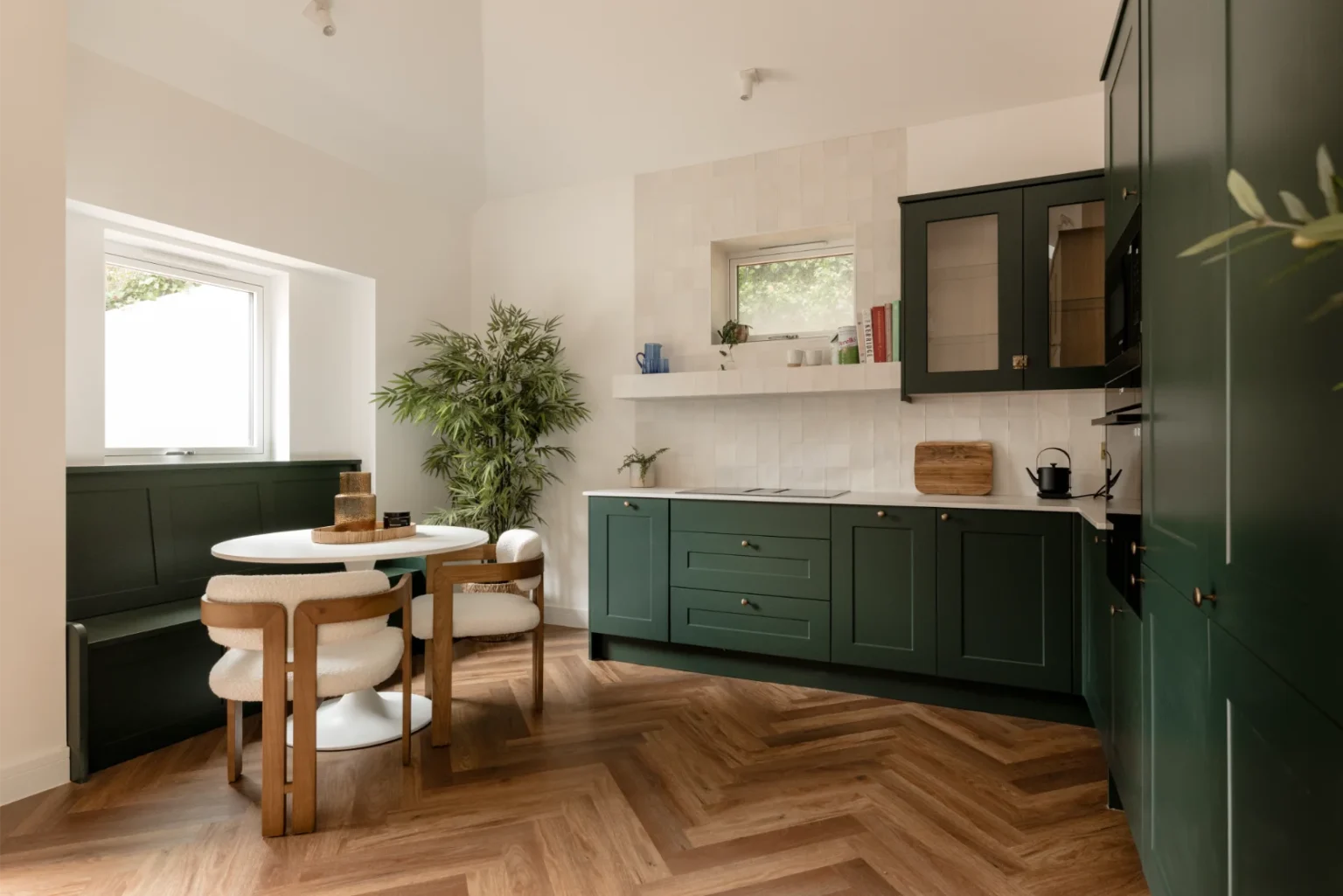 Modern kitchen with green cabinets and wood flooring.