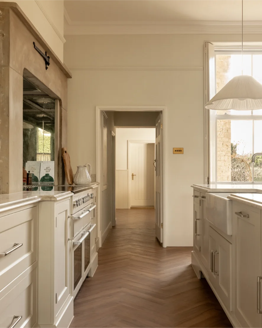 Elegant kitchen with wooden flooring and white cabinets.
