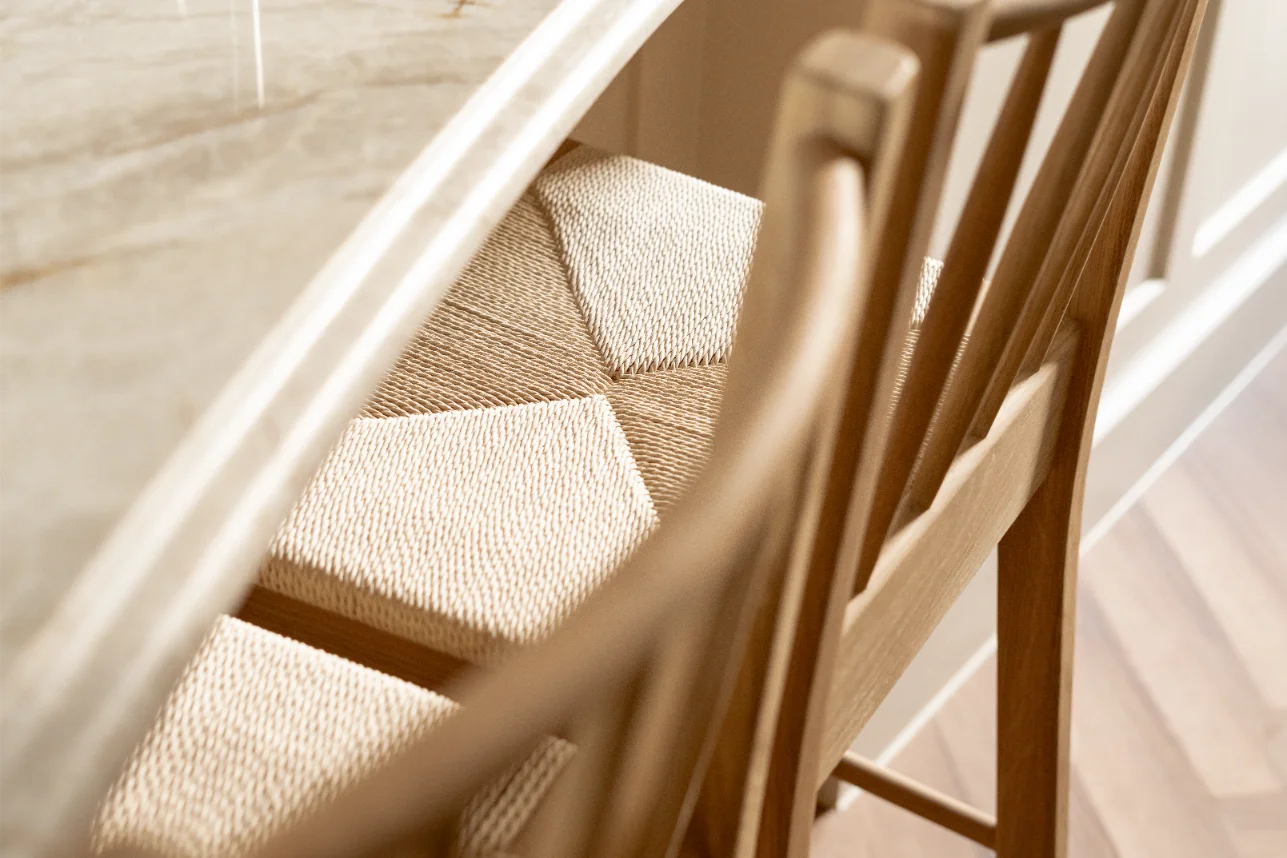 Wooden chair with woven seat by table.