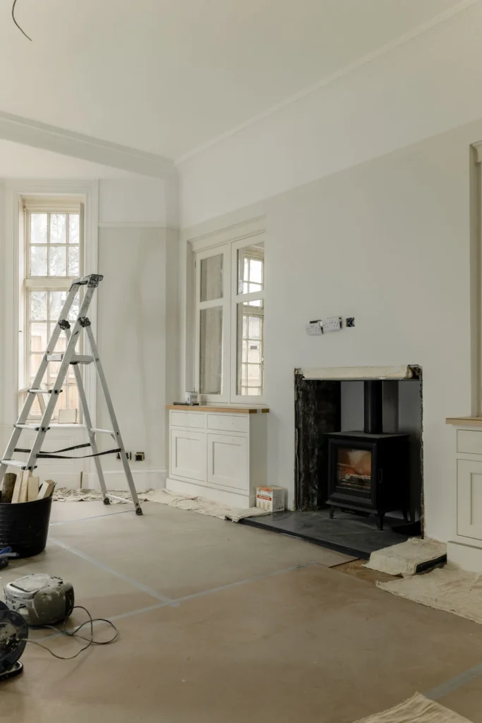 Room under renovation with ladder and fireplace.