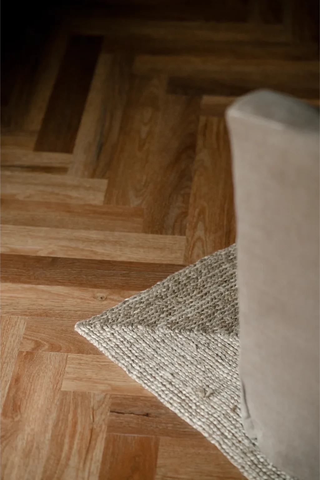 Close-up of herringbone wood floor and rug corner.