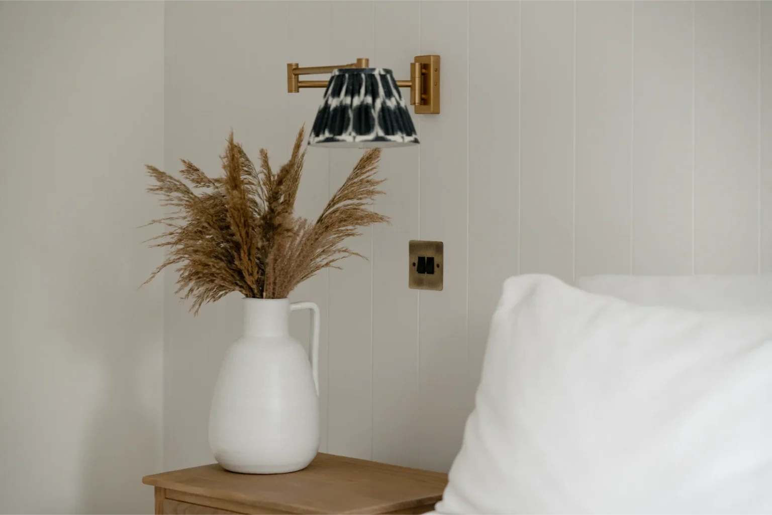 Vase with dried pampas grass on bedside table.
