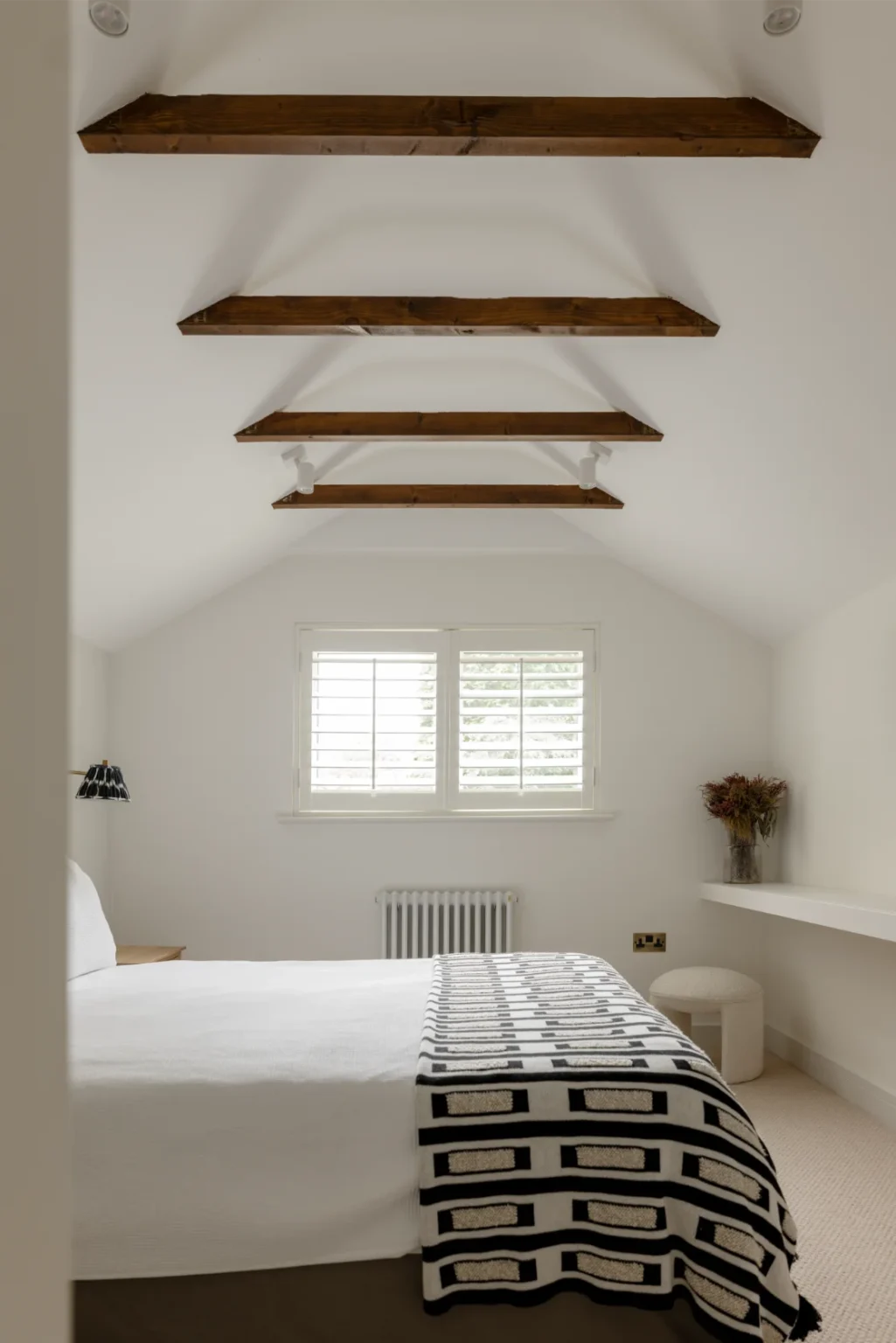 Modern bedroom with exposed wooden beams and radiator.