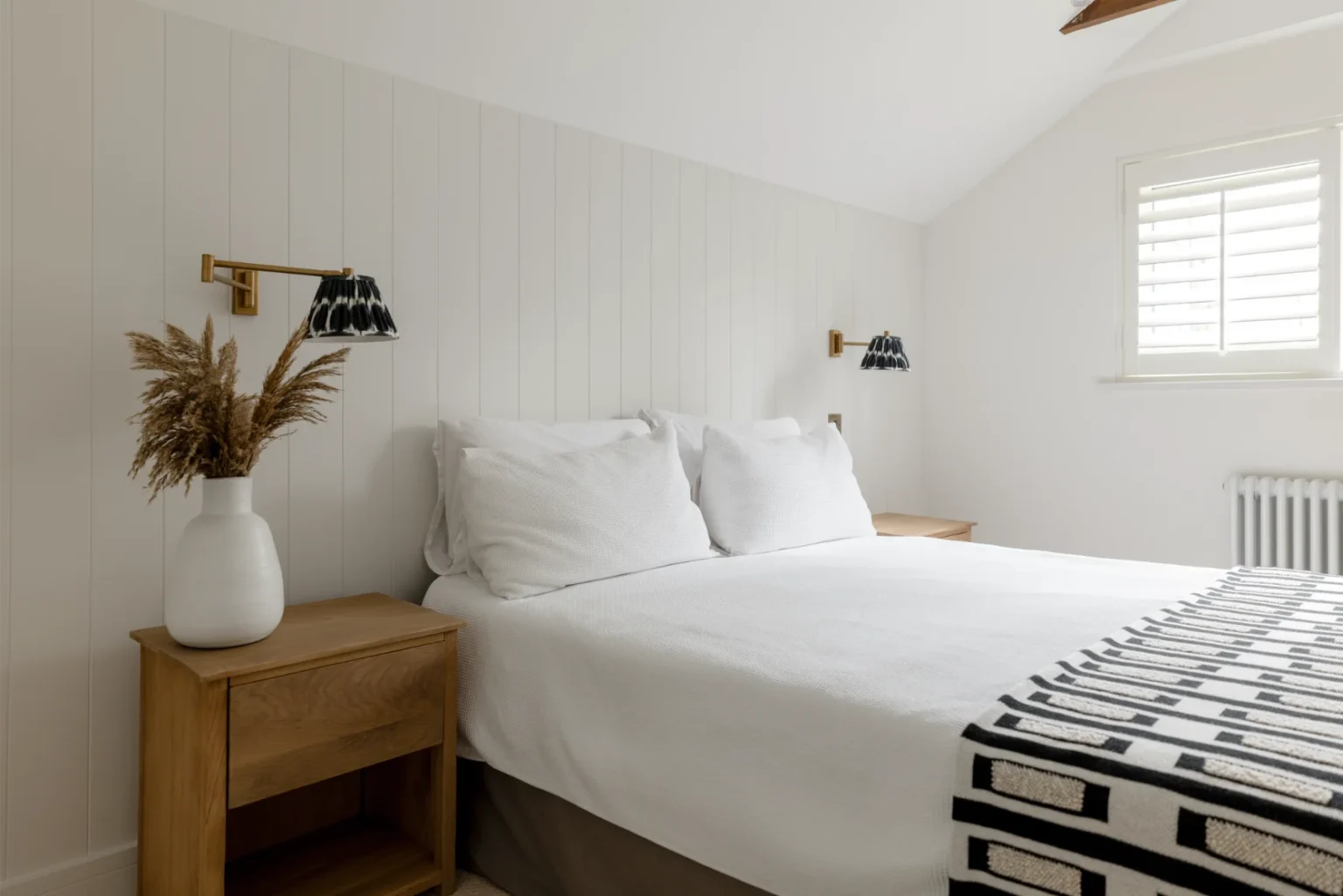 Cozy bedroom with wooden furniture and white bedding.