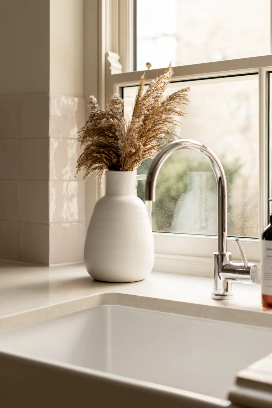 White vase with pampas grass by kitchen sink