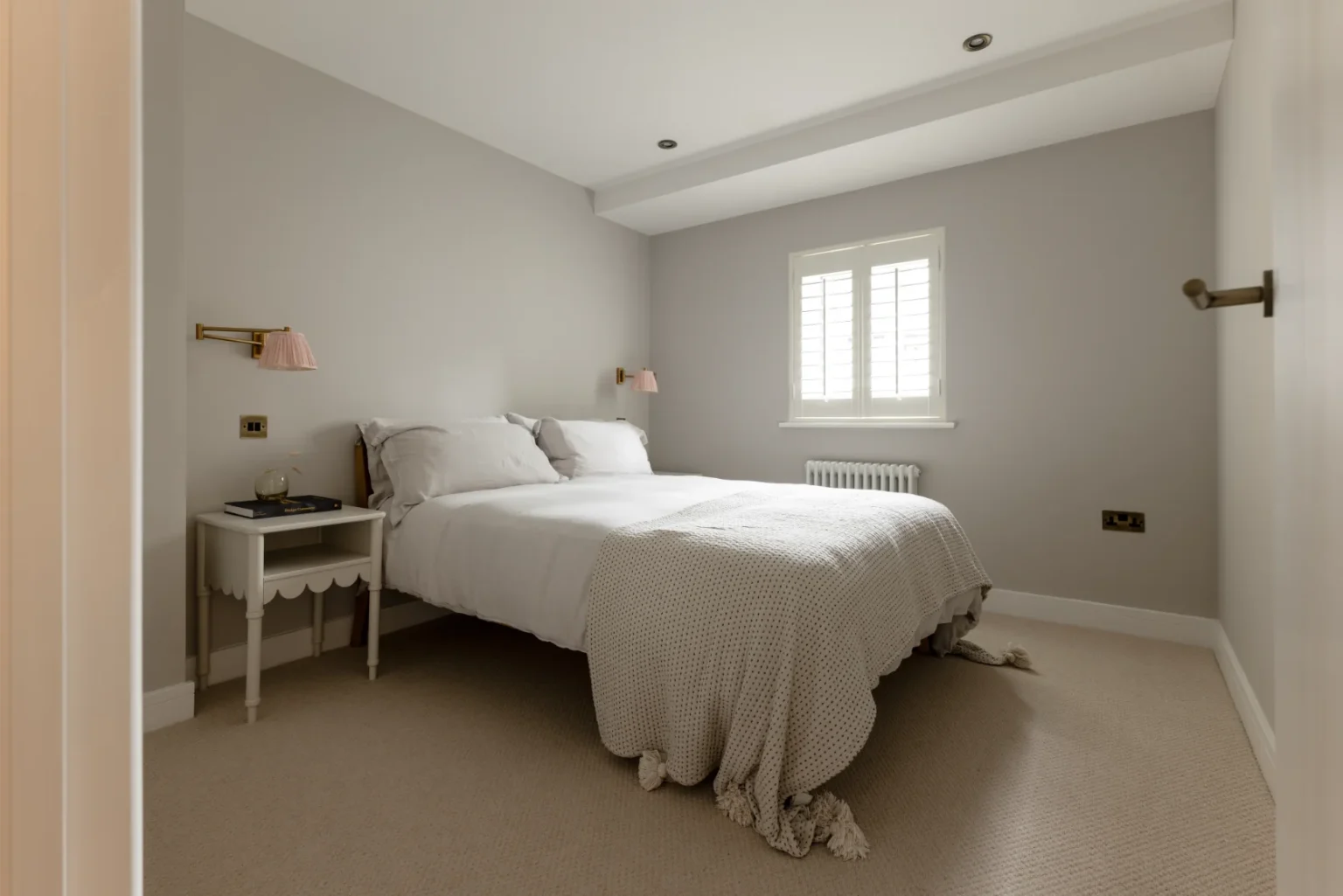 Cozy bedroom with white bed and nightstand.