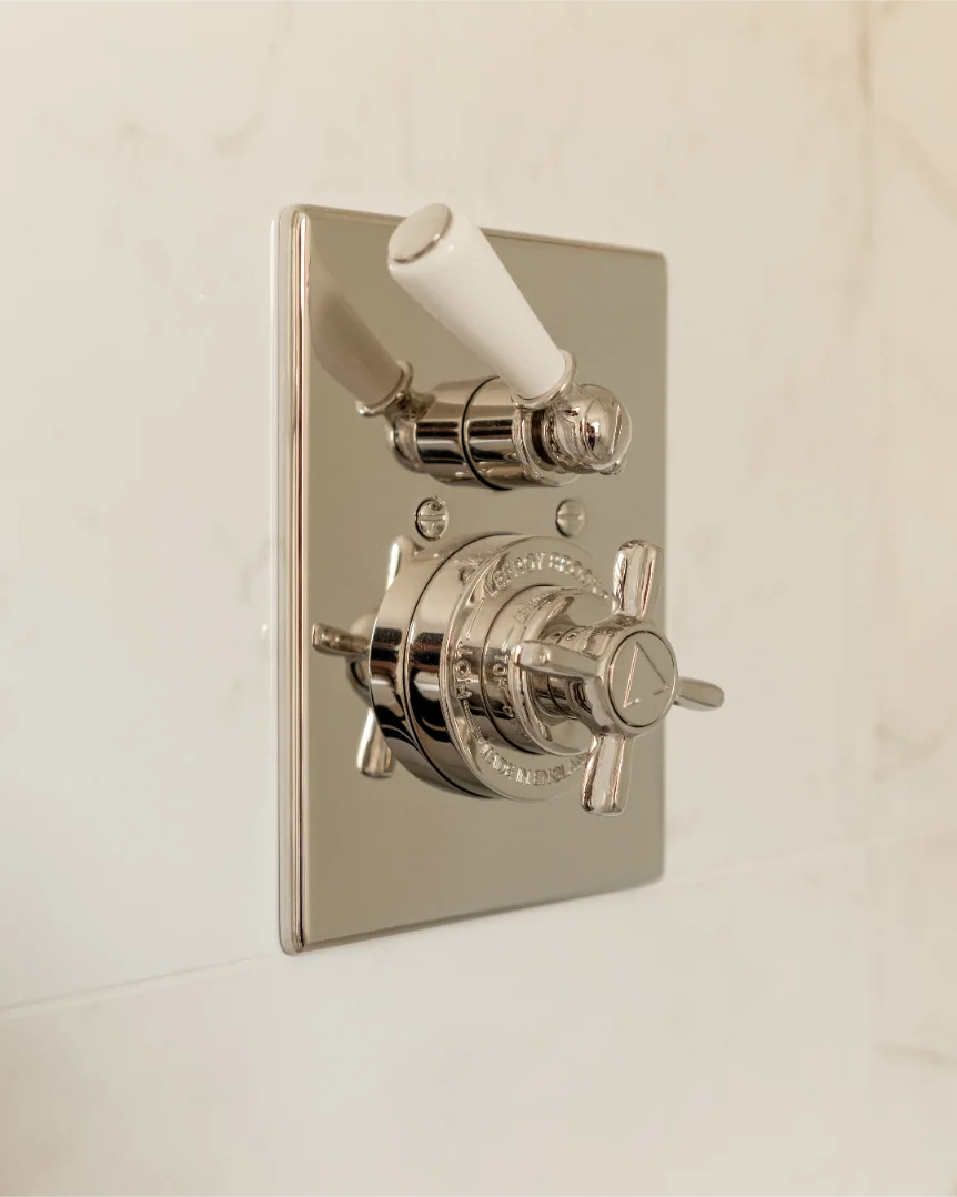 Silver shower valve on white tile wall