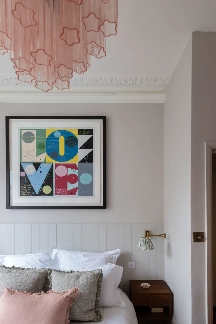 Bedroom with modern art and pink chandelier.