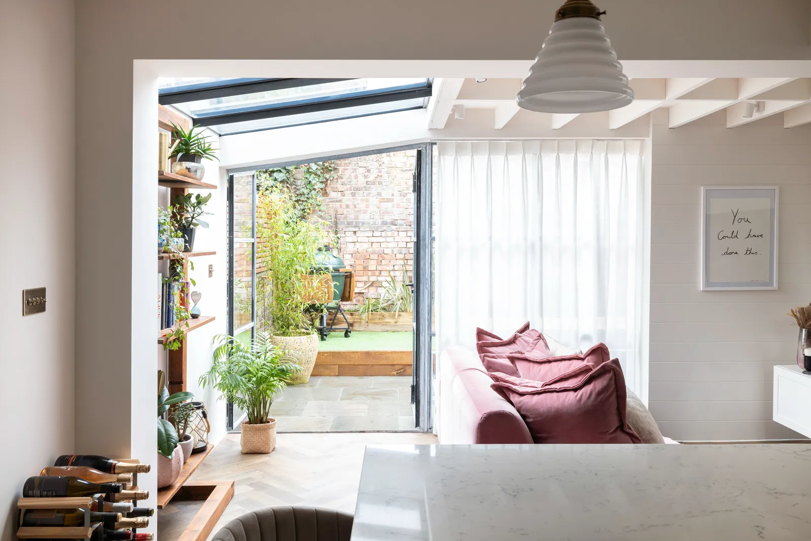 Modern living room with garden view and pink couch.